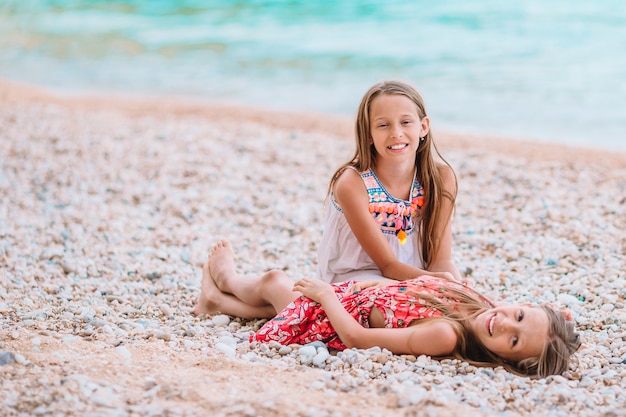 Twee kleine gelukkige meisjes hebben veel plezier op tropisch strand samen spelen