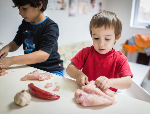 Twee kleine jongens die voedsel in de keuken voorbereiden