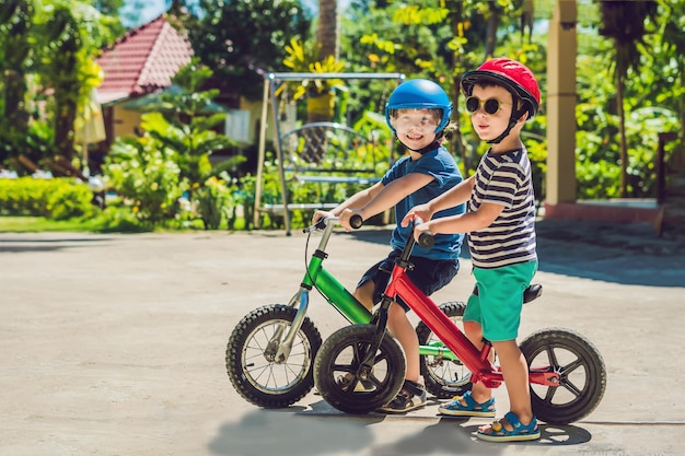 Twee kleine jongens kinderen plezier op loopfiets op een tropische landweg