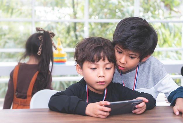 Twee kleine jongens spelen online spel op mobiele telefoon