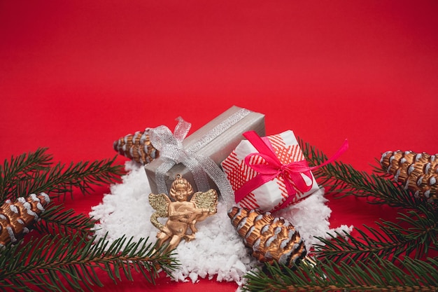 Twee kleine kerstcadeaudozen liggen in de sneeuw. Rode achtergrond. Kerstcadeaus en speelgoed.