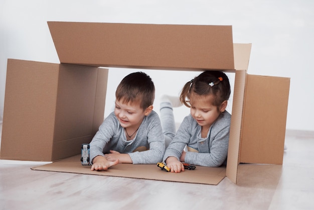 Twee kleine kinderen, jongen en meisje, zijn net verhuisd naar een nieuw huis. concept foto. kinderen hebben plezier en spelen kleine auto's