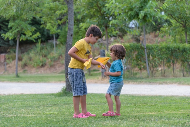 Twee kleine kinderen spelen met kartonnen speelgoed vliegtuig in het park op het moment van de dag Concept van blij spel Kind plezier buitenshuis