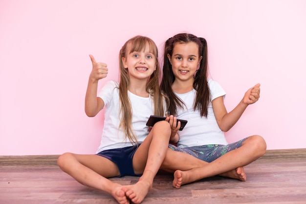 Twee kleine meisjes - beste vrienden, geïsoleerd op een roze achtergrond