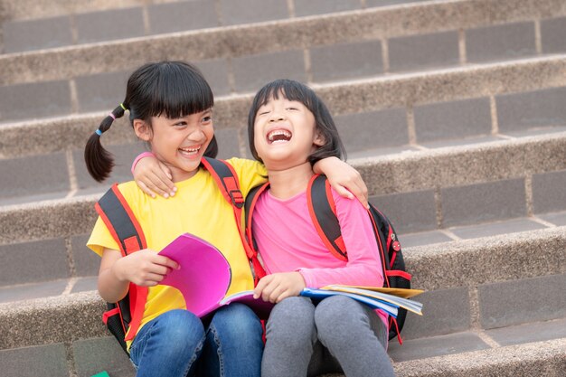 Twee kleine meisjes die samen een boek lezen. Schattige Aziatische kinderen genieten ervan om samen buiten te studeren. Onderwijs, intelligentieconcept