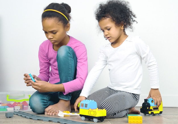 Twee kleine meisjes die stuk speelgoed spoorweg spelen. recreatie en amusement voor kinderen