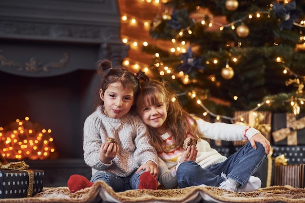 Twee kleine meisjes hebben plezier in de met kerst versierde kamer met geschenkdozen.
