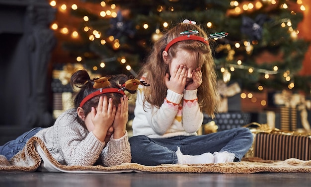 Twee kleine meisjes hebben plezier in de met kerst versierde kamer met geschenkdozen.