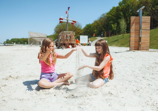 Twee kleine meisjes hebben plezier op het zandstrand, kinderen spelen met zand