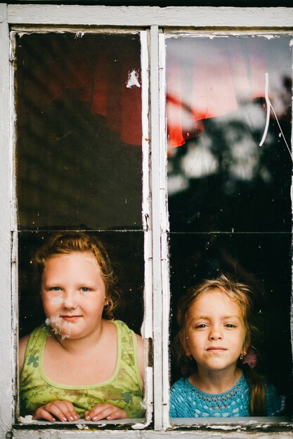 Twee kleine meisjes kijken door raam