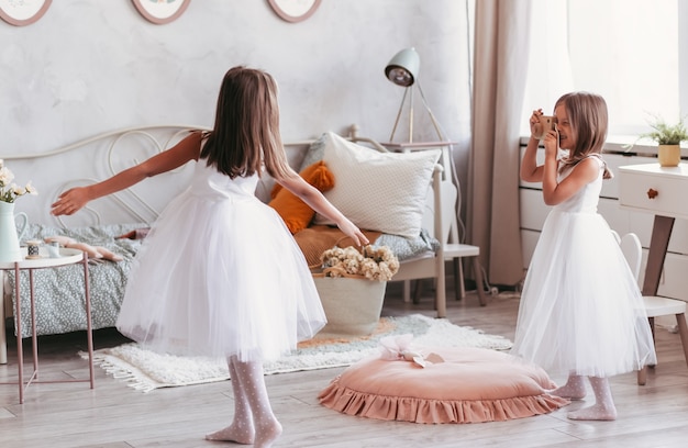 Twee kleine meisjes spelen en dansen in een grote, lichte kinderkamer. zussen brengen graag tijd samen door