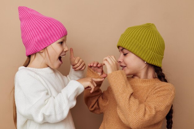 Twee kleine meisjes staan naast elkaar in hoedenmode-emoties