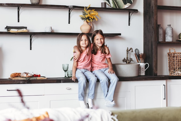 Twee kleine meisjes zittend aan de keukentafel Gelukkige levensstijl familiemomenten