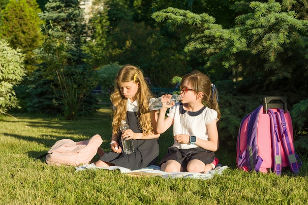 Twee kleine meisjesschoolkinderen drinken water