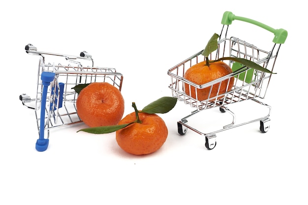 Foto twee kleine speelgoedkar voor boodschappen uit de supermarkt en drie mandarijnen met groene bladeren geïsoleerd op een witte achtergrond.