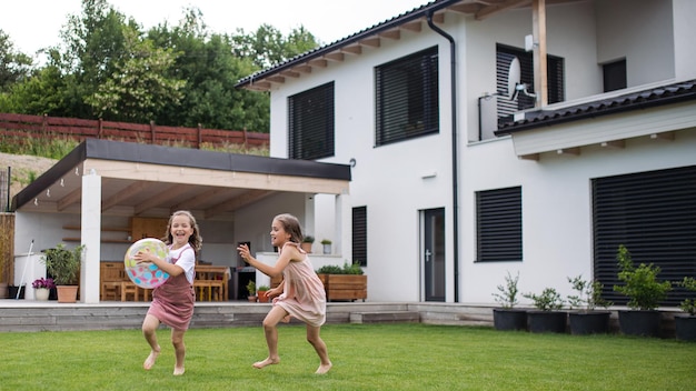 Twee kleine zusjes spelen met een bal buiten in de achtertuin.