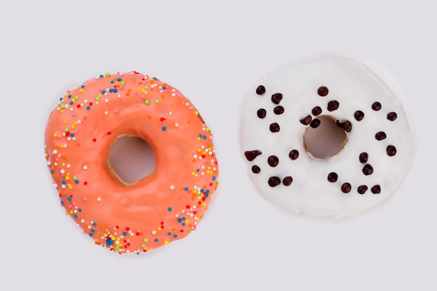 Twee kleurrijke donuts op witte achtergrond. oranje en witte donuts met hagelslag. lekker frosted dessert.