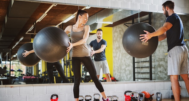 Twee knappe jongeren die pilatesballen gebruiken voor het uitoefenen in een gymnastiek.