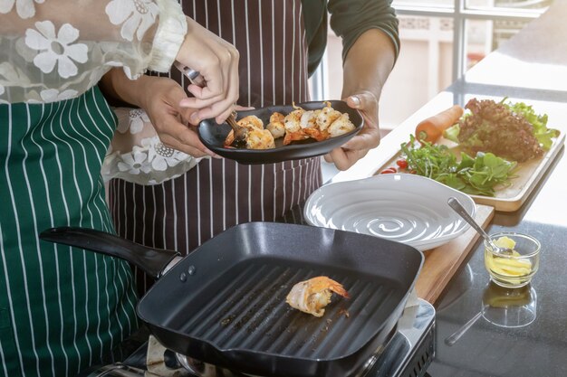 Twee koks helpen garnalen bakken in de keuken.