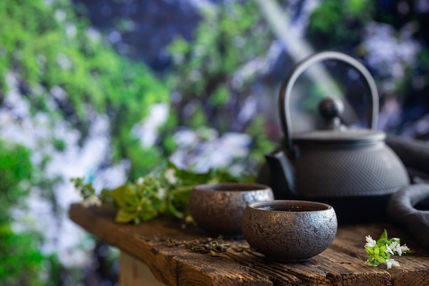 Twee kopjes groene thee en theepot op houten tafel en natuurachtergrond met kopieerruimte