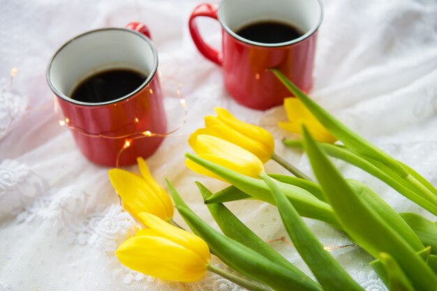 Twee kopjes koffie en een boeket heldere tulpen