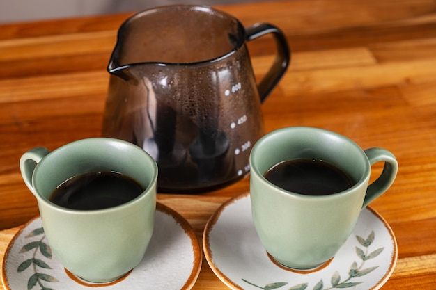 twee kopjes koffie en een zeef gebruikt op de achtergrond