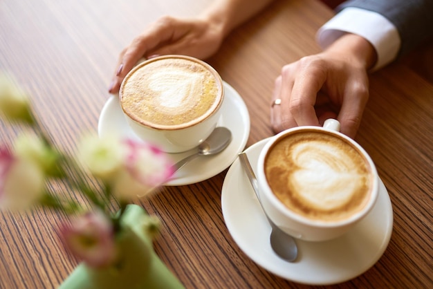 Twee kopjes koffie met decoratieve vilten hartjes vastgebonden op de handvatten voor de trouwdag