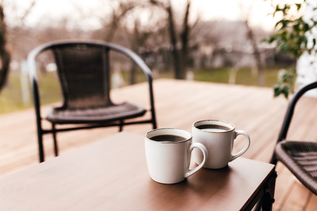 Twee kopjes koffie op de tafel op het houten bruine terras tijdens zonsondergang. Ontspanning, liefhebbers van romantisch avondconcept