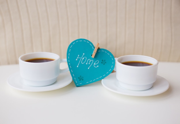 Twee kopjes koffie op tafel en een hart