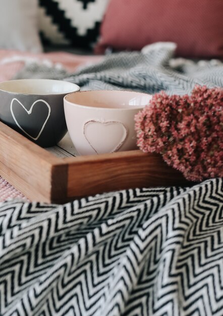 Twee kopjes met een hart op het bed met bloemen