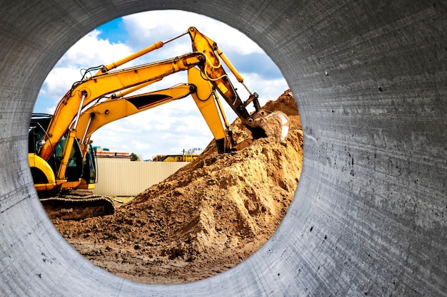 Twee krachtige graafmachines werken tegelijkertijd op een bouwplaats zonnige blauwe lucht op de achtergrond bouwmachines voor grondwerken uitzicht vanaf een grote betonnen pijp