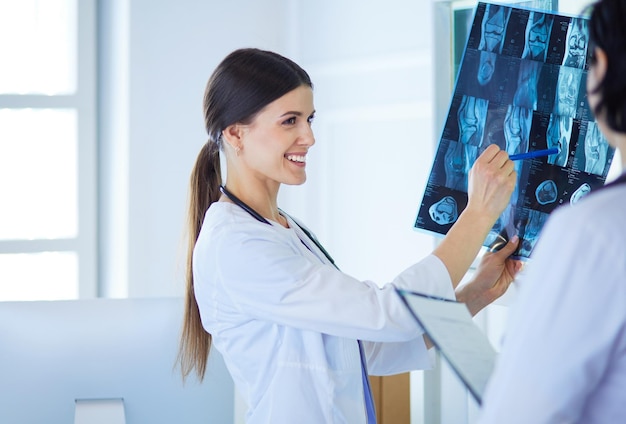 Twee lachende artsen wijzen op röntgenfoto's in een spreekkamer in een ziekenhuis