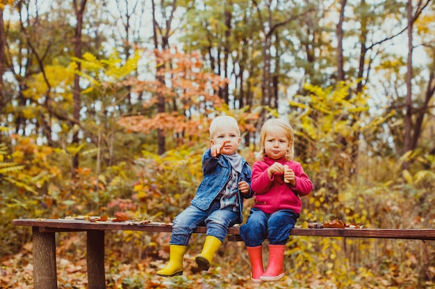 Twee lachende happy kids vrienden, jongen en meisje zittend op de bank in het park