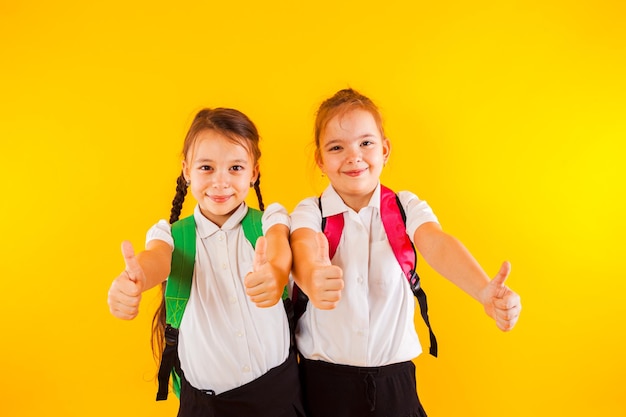 Twee lachende schoolmeisjes van een basisschool wijzen duimen omhoog