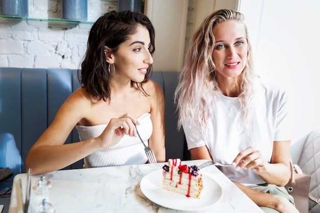 Twee lachende vriendinnen eten een toetje in een café De vreugde van communicatie, liefde en tederheid