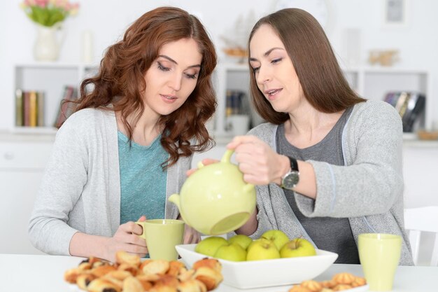 Twee lachende vriendinnen zitten aan tafel