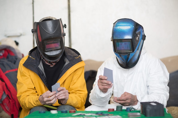 Twee lassers in lasmaskers spelen poker