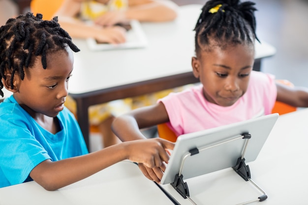 Twee leerlingen die tabletpc gebruiken bij hun bureau