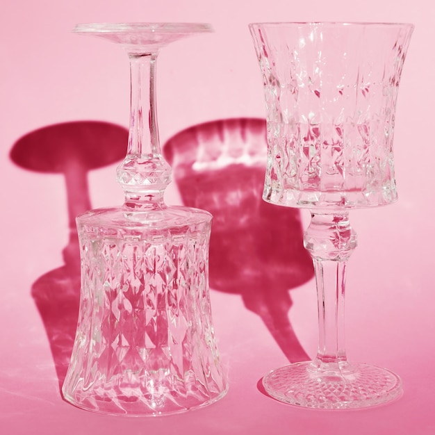 Twee lege kristallen glazen op een steel op een roze achtergrond Wijnavond samen