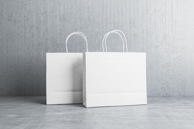 Twee lege witte papieren boodschappentassen met plaats voor uw logo of tekst op betonnen vloer op grijze muur achtergrond 3D-rendering mock up