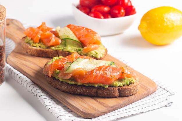 Foto twee lekkere open broodjes zalm met avocado en komkommer. ochtend gezond ontbijt. bovenaanzicht.