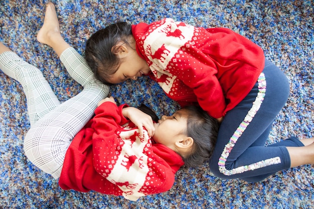 Twee leuke aziatische kindmeisjes die op de vloer bepalen en spelen samen in kerstmisviering