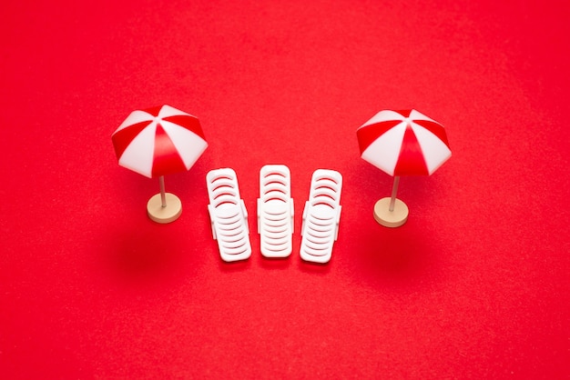 Twee ligstoelen en rode parasols op een rode achtergrond. Ruimte kopiëren.