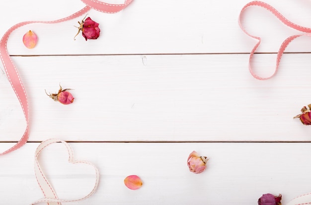 Twee lint magische roze harten op witte houten backround, rozen en bloemblaadjes. Valentijnsdag concept