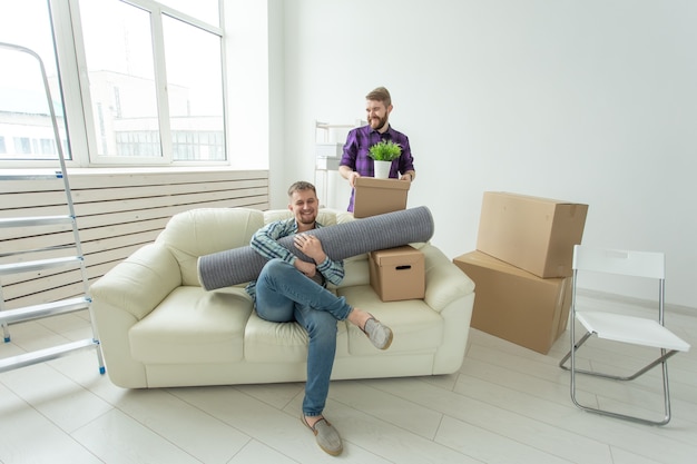 Twee mannelijke studentenvrienden die hun spullen in hun handen houden die in de woonkamer van nieuw zitten