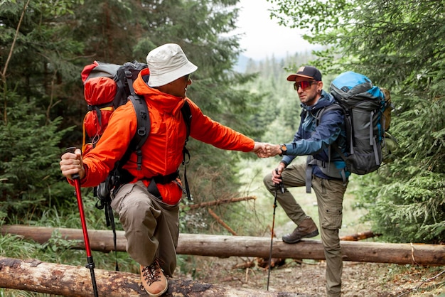 Foto twee mannelijke toeristen met rugzakken en wandeluitrusting lopen samen in het bos