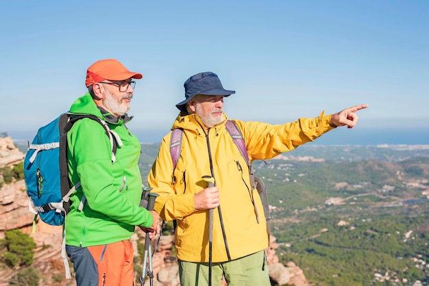 Twee mannelijke volwassen wandelaars op de top van het avontuur van bergmensen en actief pensioenconcept