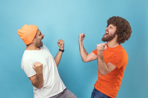 Twee mannen die ja-gebaar tonen en schreeuwen om overwinningssucces te vieren, dromen komen uit