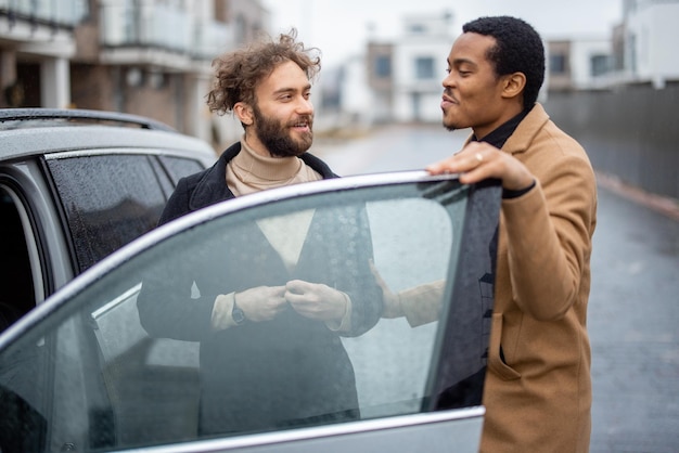Foto twee mannen flirten terwijl ze op straat bij de auto staan