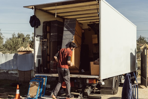 Twee mannen laden een meubelstuk op een rijdende vrachtwagen